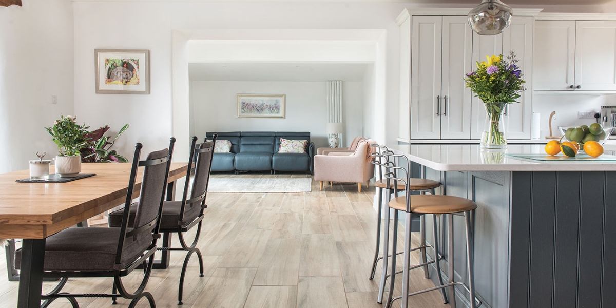 A large open plan living area with a dining area to the left, sofa in front and a fitted kitchen on the right.