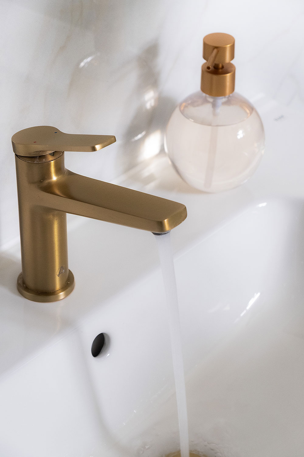 A brushed brass tap running.