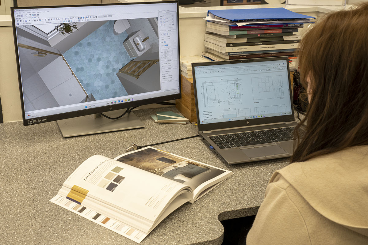 An image over our bathroom designer, Lucy's shoulder looking at a computer screen with a bathroom on it.